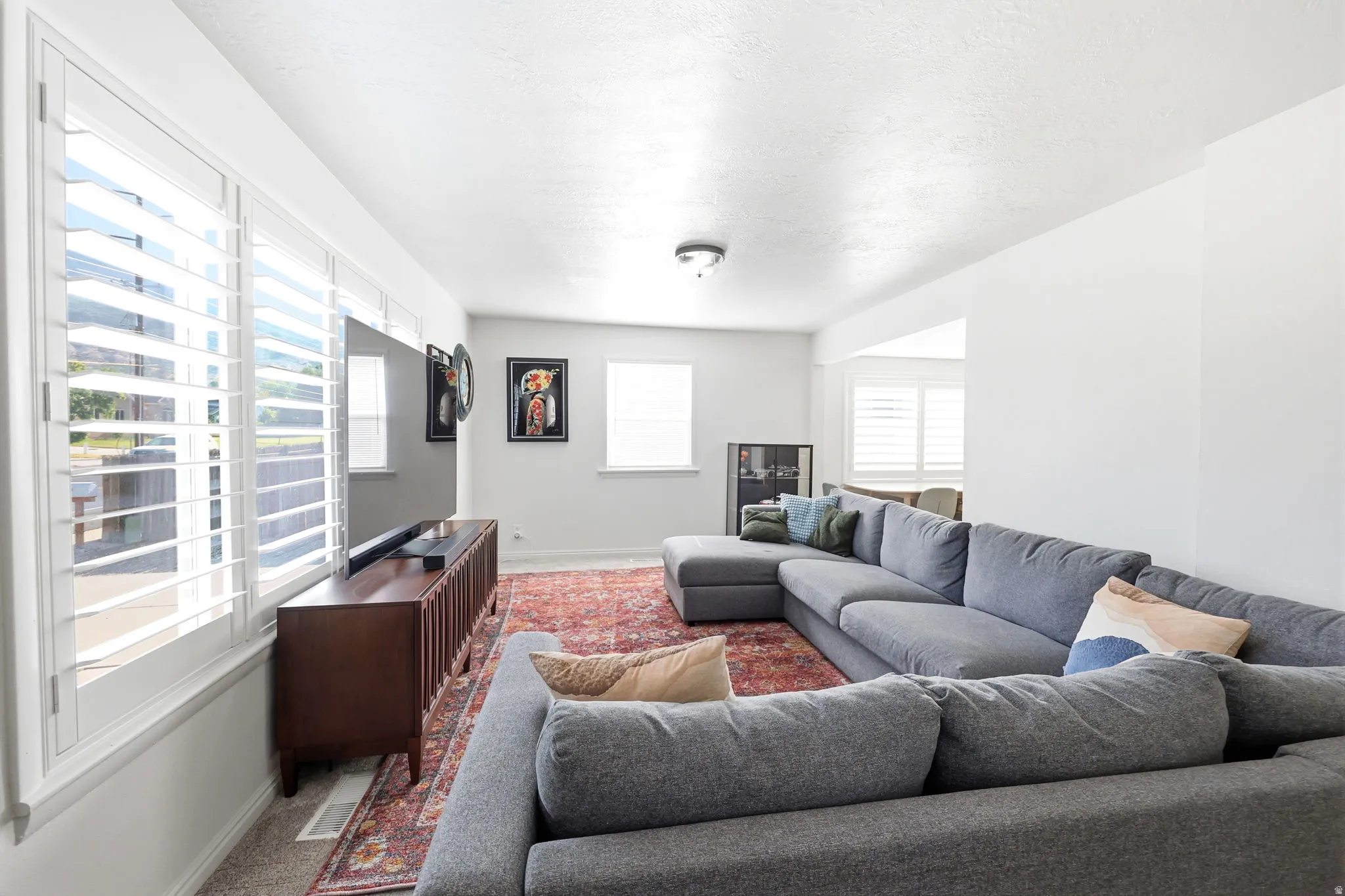 Bright living space featuring white walls and white plantation shutters on multiple windows