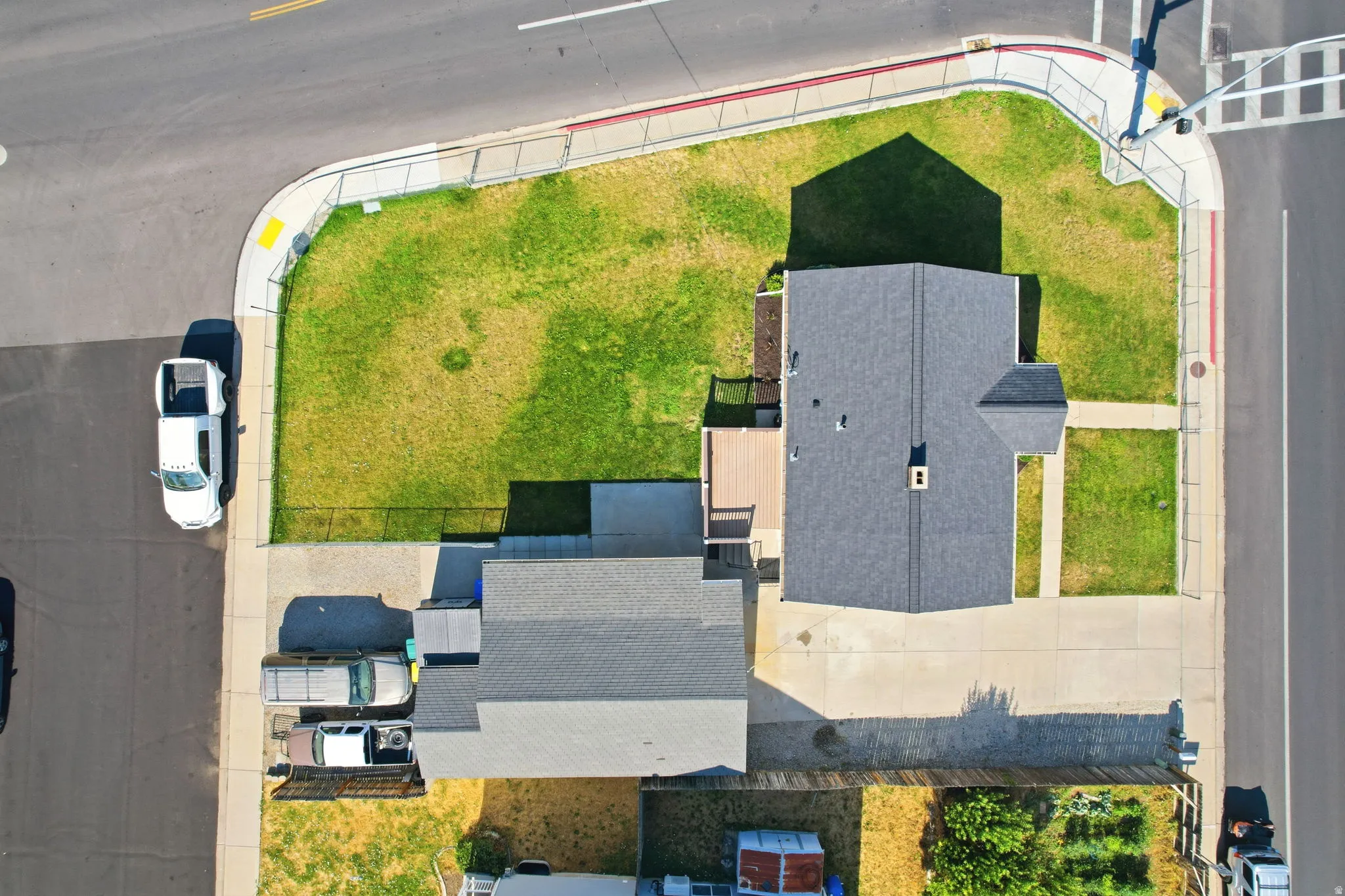 Property featuring a spacious corner lot, asphalt shingle roofing, a concrete driveway, an additional gravel parking area, and a rear deck