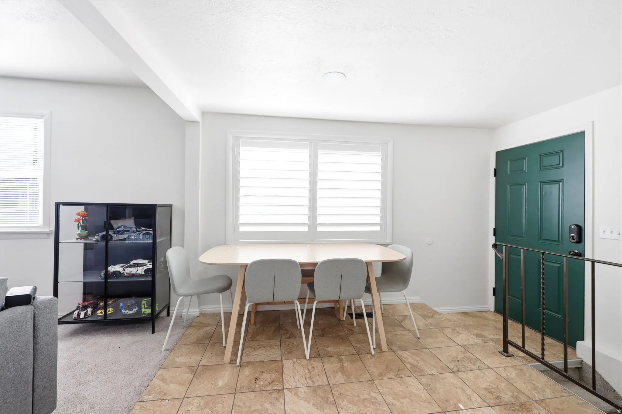 Transitional entry area with a paneled front door, an adjacent window with plantation shutters, and light-toned tile flooring