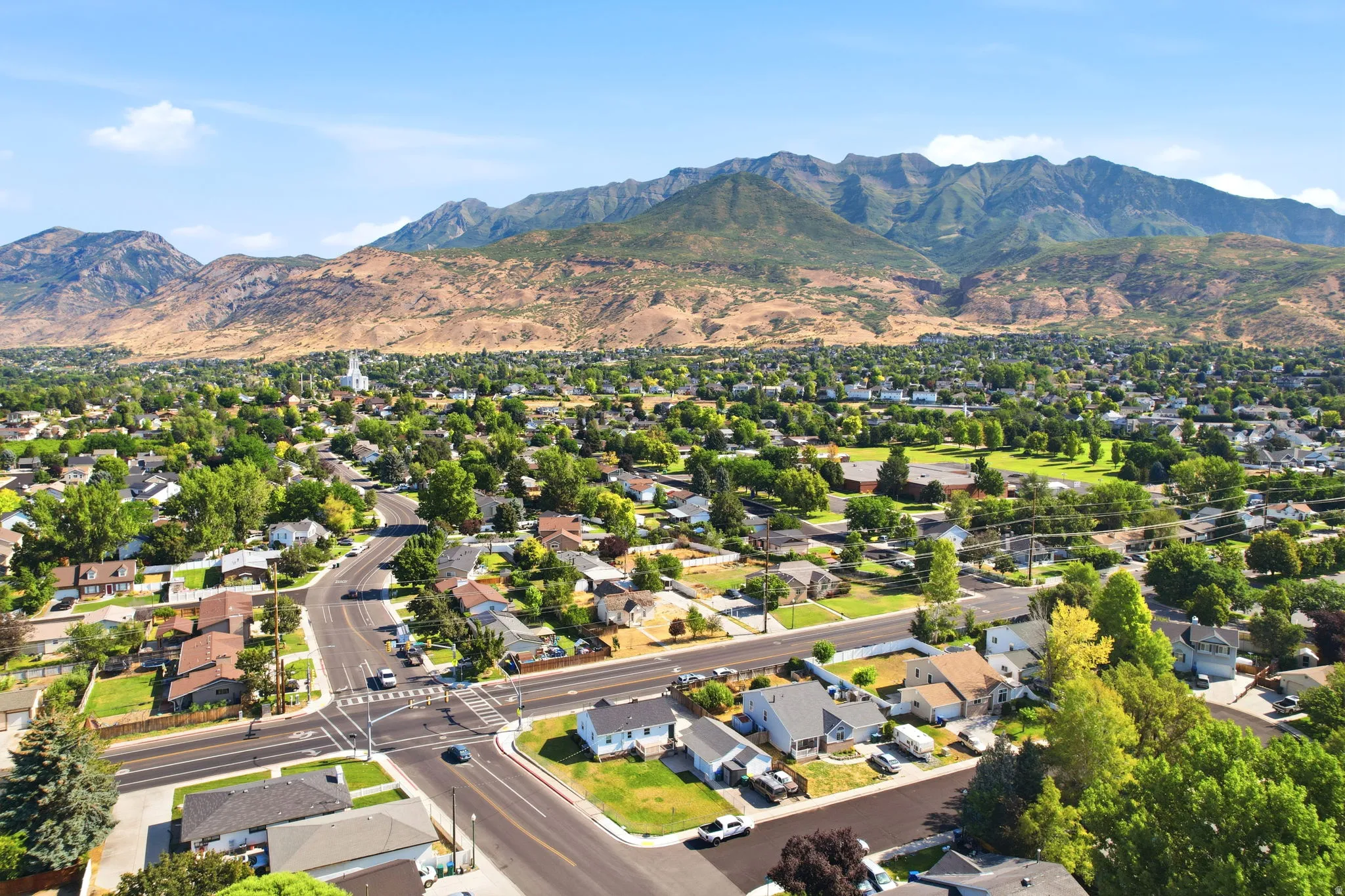Expansive residential area featuring established homes, mature trees, open green spaces, and mountain backdrops