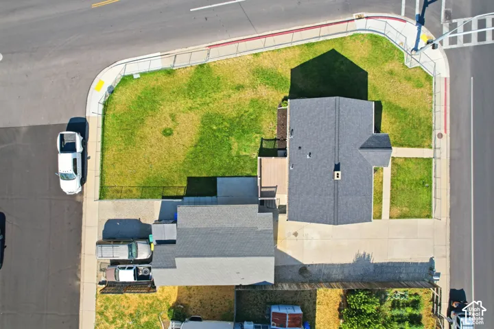 Property featuring a spacious corner lot, asphalt shingle roofing, a concrete driveway, an additional gravel parking area, and a rear deck