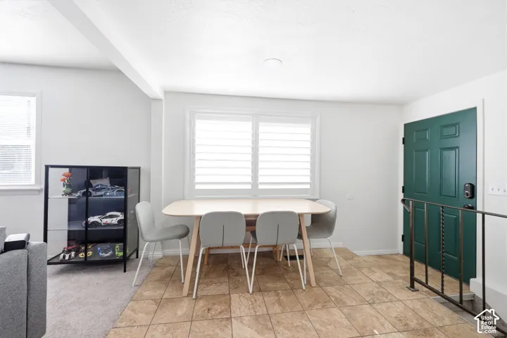 Transitional entry area with a paneled front door, an adjacent window with plantation shutters, and light-toned tile flooring