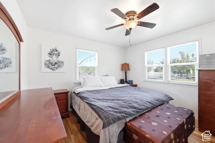 Bright room featuring wood-finish flooring, white walls, and a ceiling fan with integrated lighting