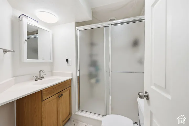 Bathroom with a light wood-finish vanity, white countertop, and integrated sink