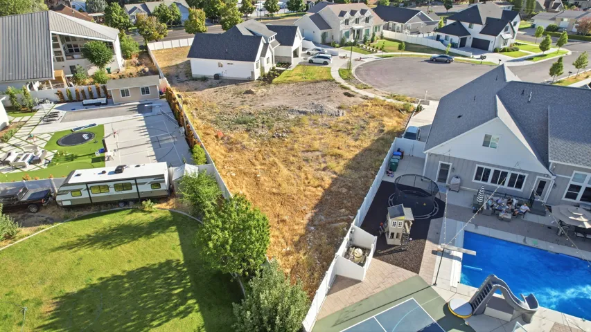 Expansive undeveloped lot featuring a triangular shape, perimeter fencing, and surrounding residential properties