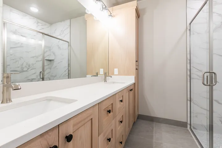 Double vanity with integrated sinks, brushed nickel fixtures, and a light wood-finish cabinetry