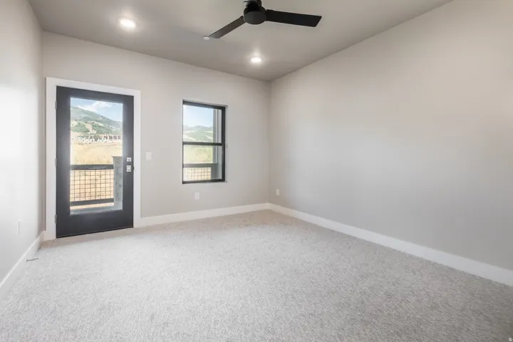 Carpeted room featuring a full-light exterior door with a black frame and hardware, a single window with black framing, a black ceiling fan, and recessed lighting