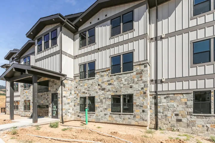 Multi-story facade featuring board and batten siding with stone veneer accents