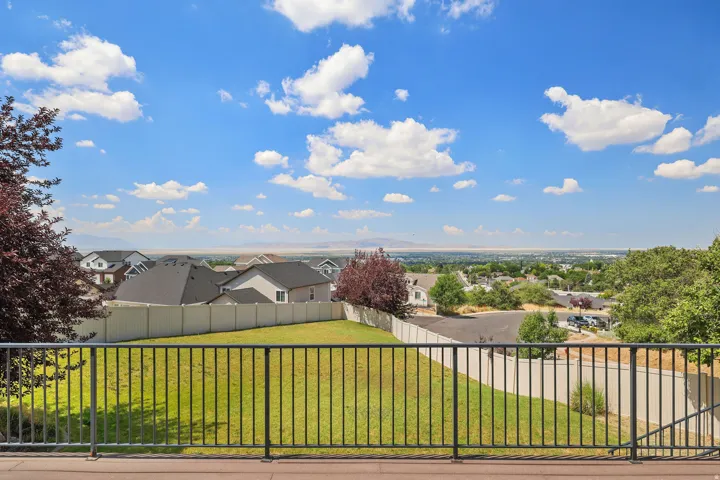 Expansive backyard with a manicured lawn, framed by a black metal railing
