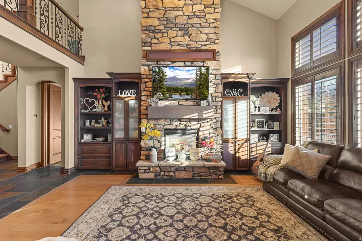 Two-story living area featuring a floor-to-ceiling stone fireplace, high ceilings, and built-in wood cabinetry