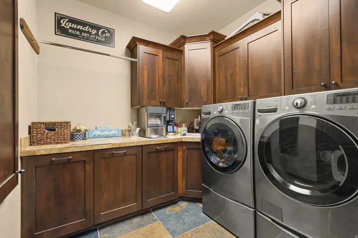 Utility room featuring dark wood-finish cabinetry, light-toned countertops, and multi-tone slate flooring