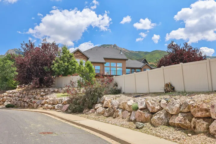 Terraced rock landscaping with mature foliage and a neutral tone privacy fence
