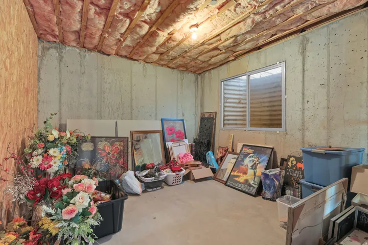 Unfinished basement area featuring exposed concrete walls and an egress window
