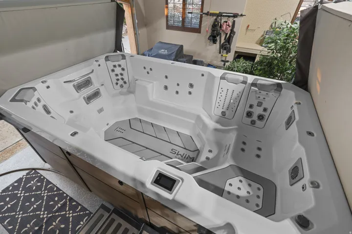 Large swim spa featuring a wood-look exterior and light-toned interior, multiple jet configurations, and a digital control panel