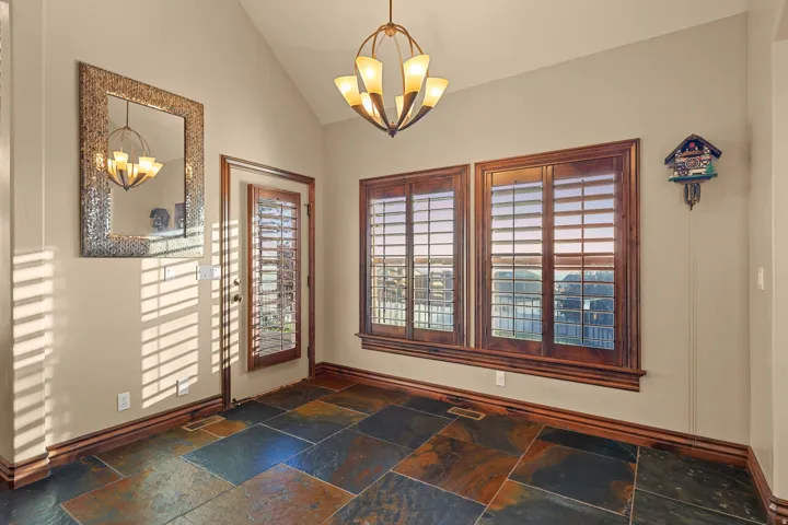 Dining room featuring varied slate tile flooring, rich wood trim, and a vaulted ceiling