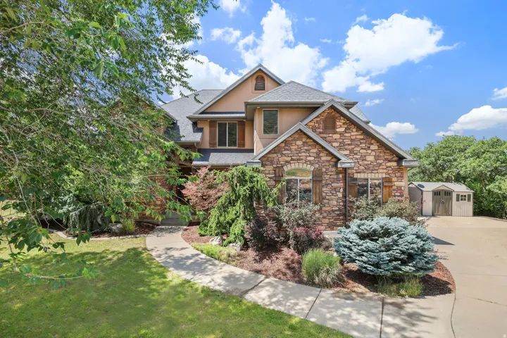 Stone and stucco exterior with multiple gables and a dark shingle roof