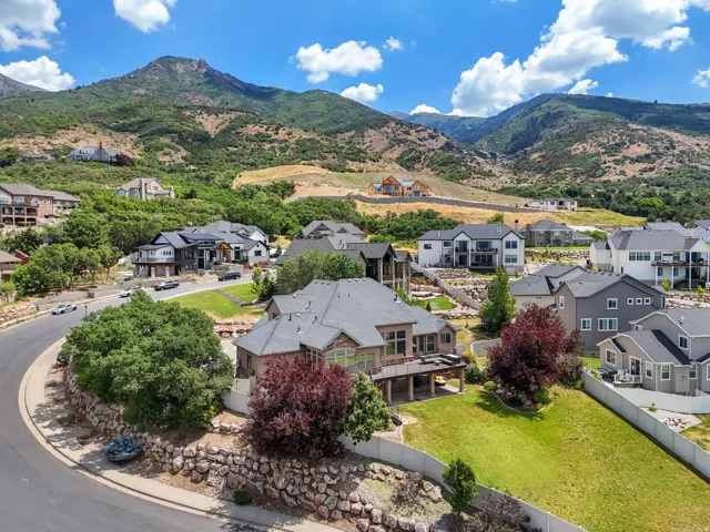 Expansive residential property featuring a multi-level deck, a manicured lawn, and mature landscaping
