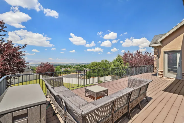 Expansive outdoor deck featuring composite decking, black metal railing, and a stucco exterior with stone accents