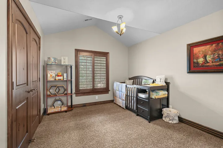 Vaulted ceiling room featuring warm neutral walls and textured carpeting
