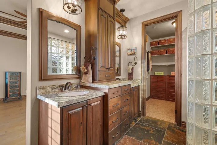 On-suit bathroom with double vanity featuring granite countertops, wood cabinetry, and vessel sinks