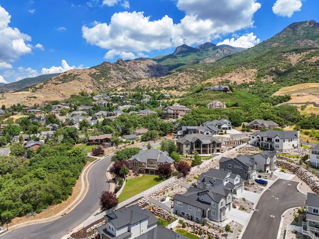 Residential neighborhood featuring a paved winding road, established homes, and natural landscaping set against a backdrop of mountainous terrain