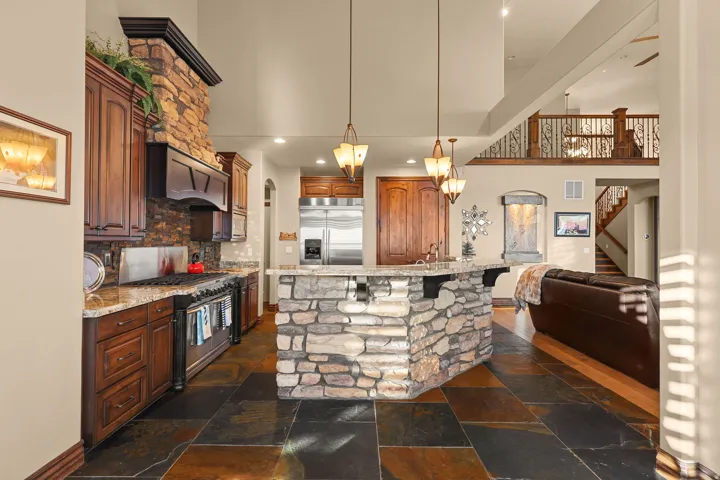 Kitchen featuring dark wood cabinetry, a stone-clad range hood, and a stone-clad island with a granite-style countertop