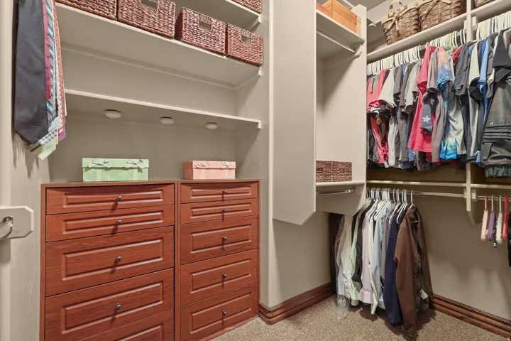 Custom closet system featuring built-in wood-finish drawers, integrated shelving, and multiple hanging rods