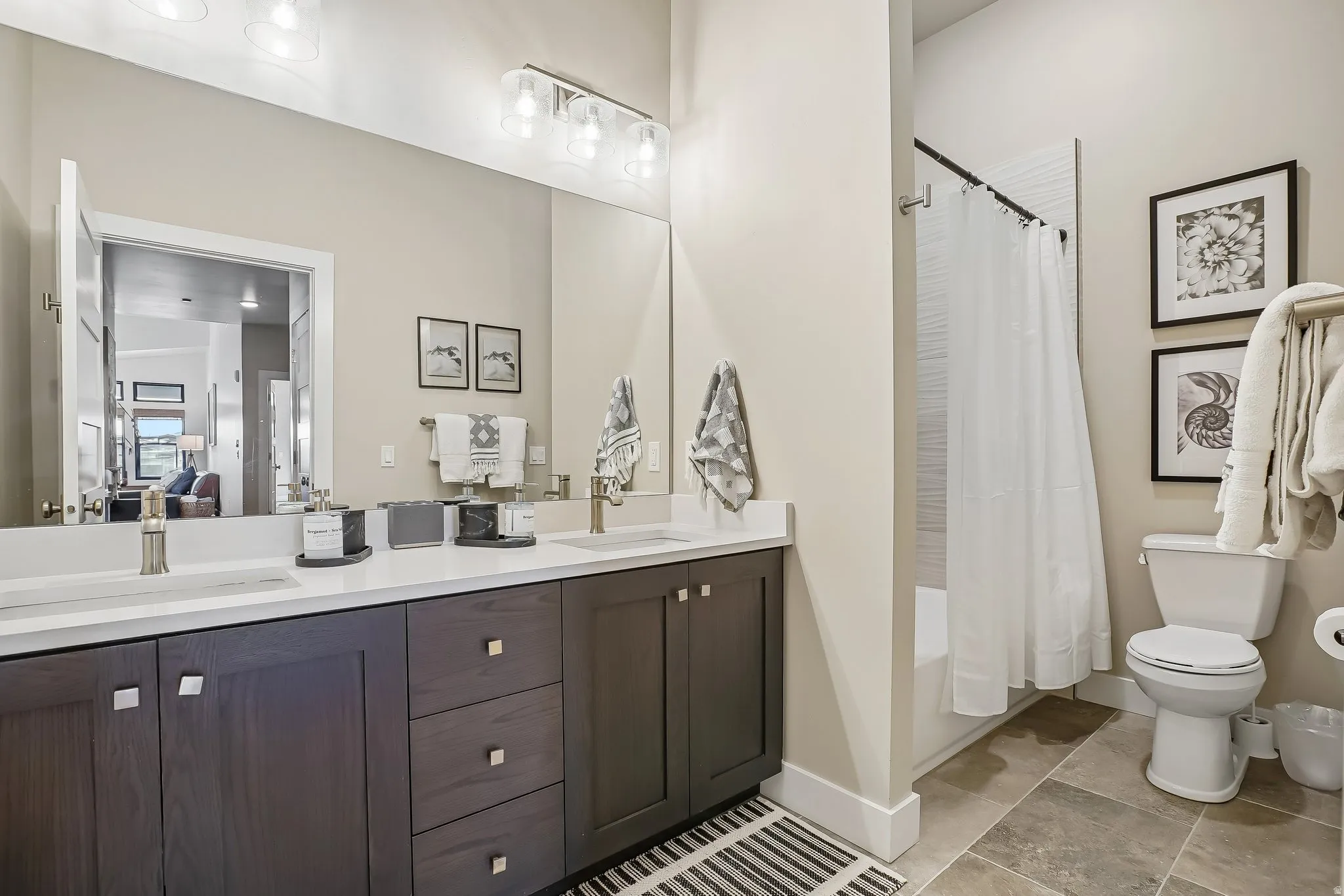 Bathroom featuring a dual vanity with white countertops, dark wood cabinetry, and brushed nickel hardware
