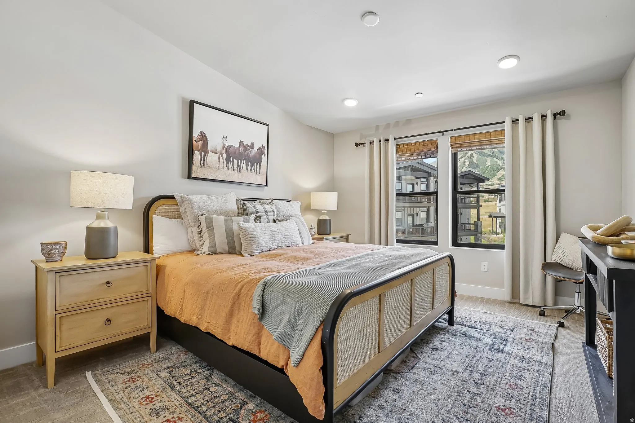Bedroom featuring recessed lighting, a vaulted ceiling, wood-finish flooring, and two large windows with mountain scenery