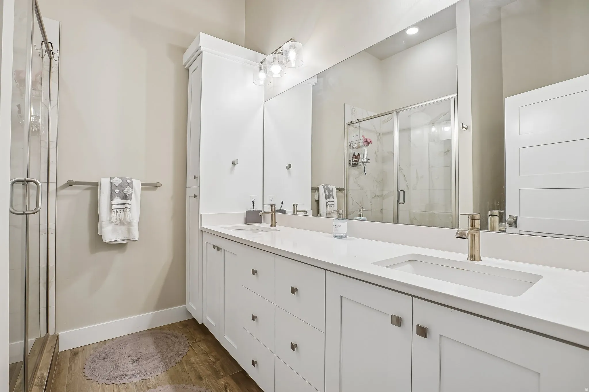 Modern bathroom featuring a dual vanity with white cabinetry, integrated sinks, and brushed gold fixtures