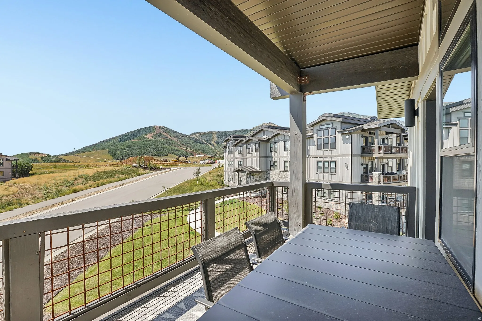 Covered exterior balcony featuring a mountain backdrop, a metal grid railing, and a wood-finish ceiling