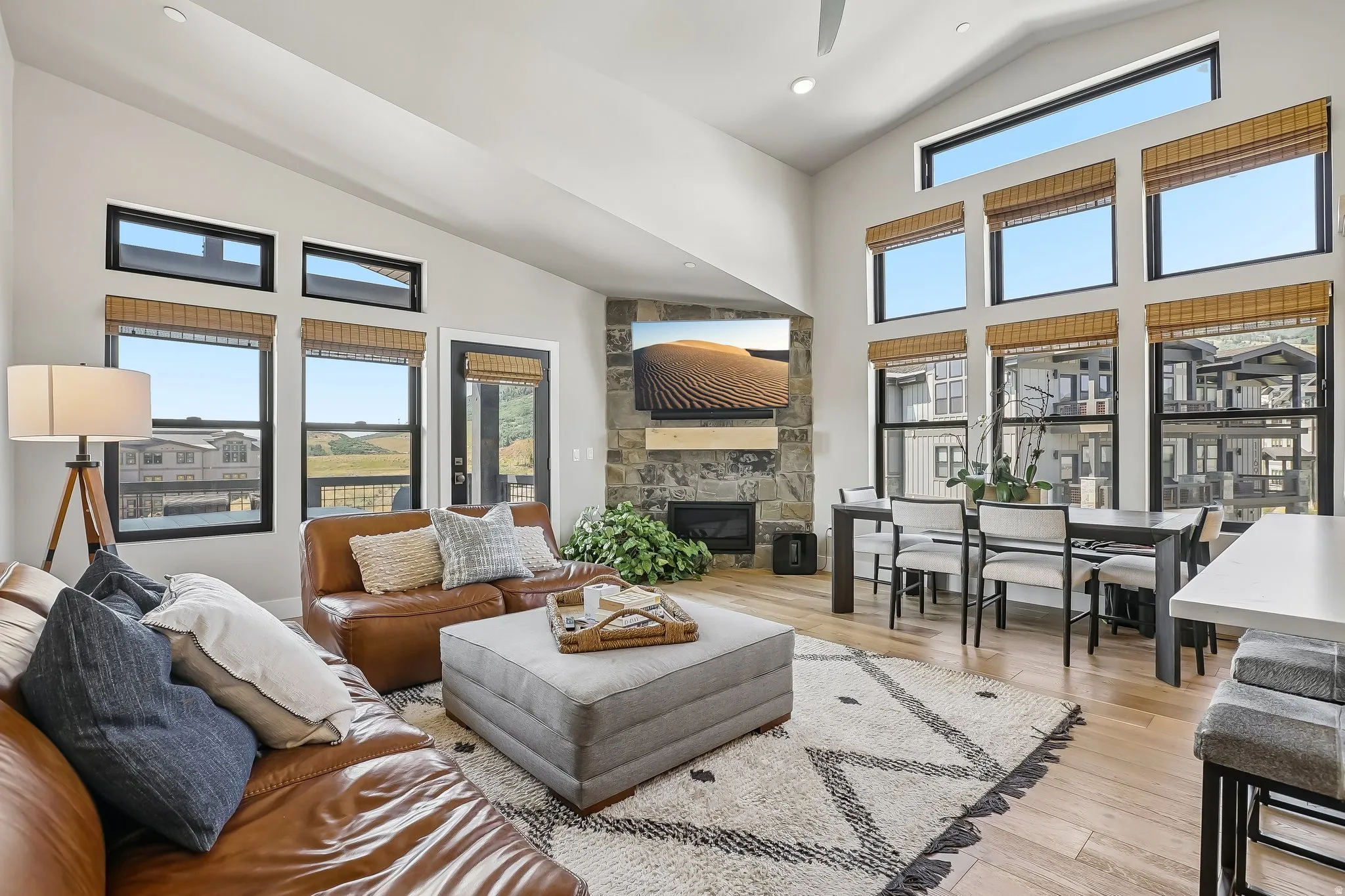 Great room featuring vaulted ceilings and abundant natural light from numerous black-framed windows