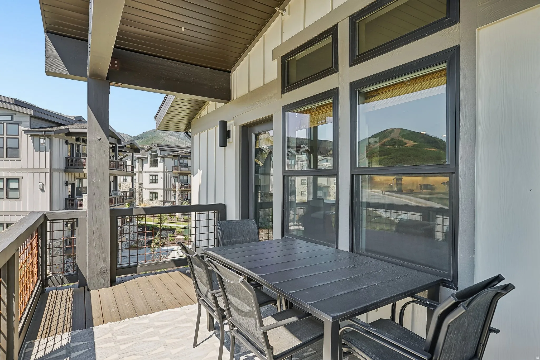 Outdoor balcony featuring wood-finish decking, dark framed windows, and metal railing