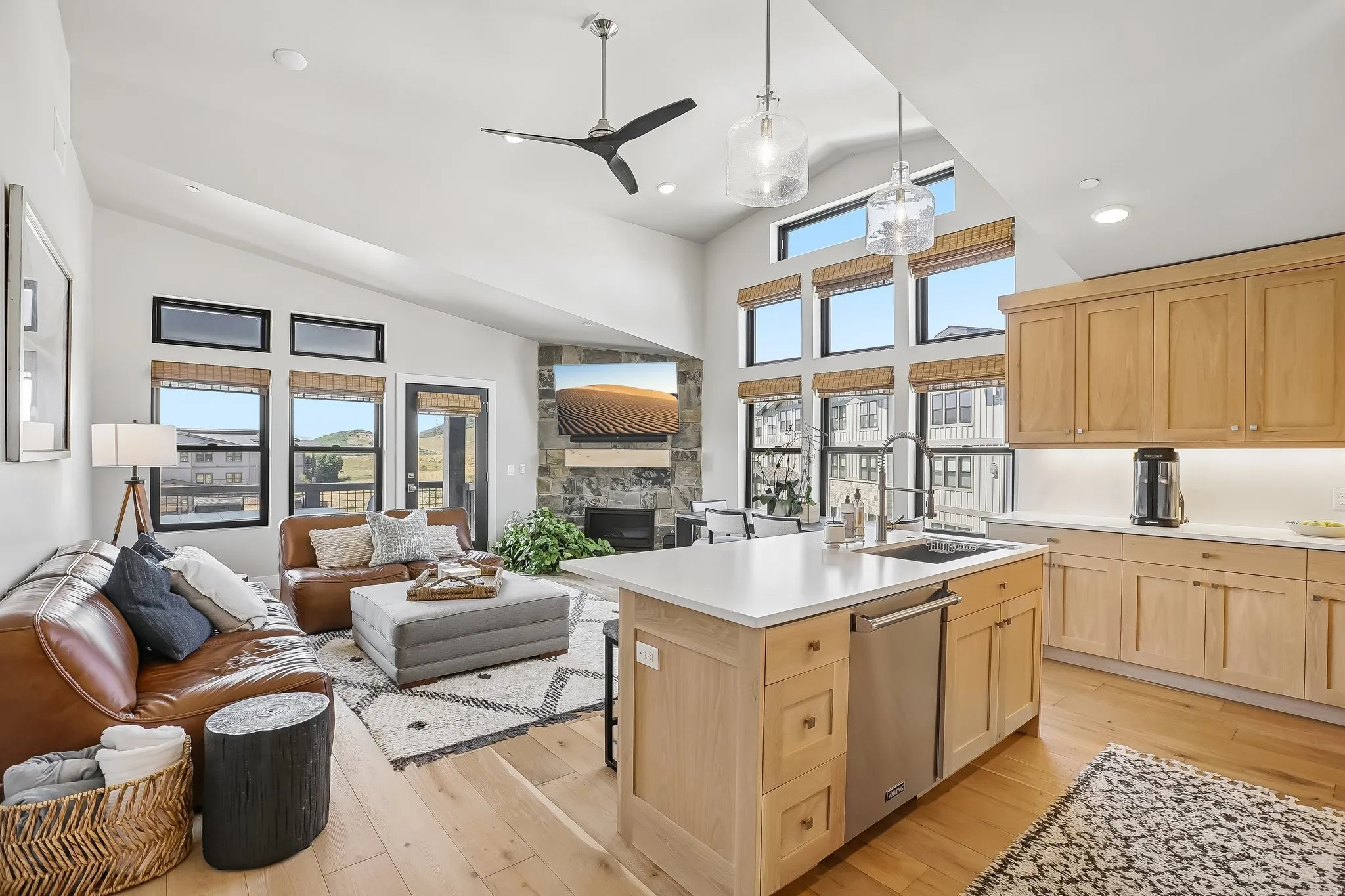 Open-concept living area featuring vaulted ceilings, a contemporary ceiling fan, and light wood-finish flooring