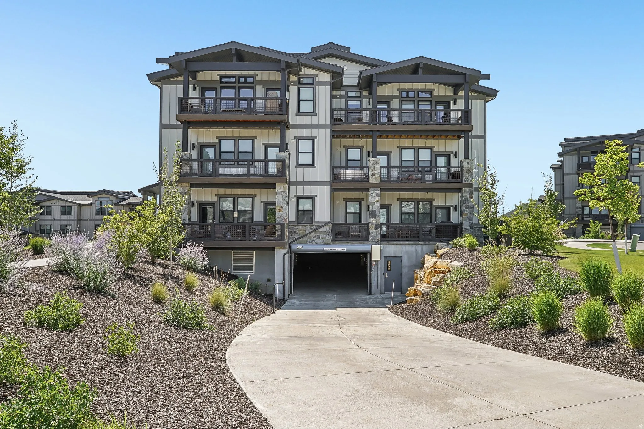 Contemporary multi-story building featuring stacked balconies and a lower-level parking garage