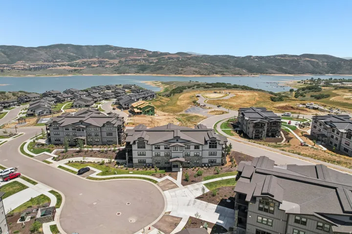 Community featuring contemporary multi-story residences with stone and siding exteriors, surrounded by landscaped grounds and paved roadways
