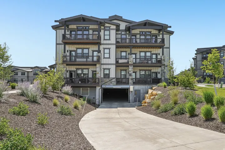 Contemporary multi-story building featuring stacked balconies and a lower-level parking garage