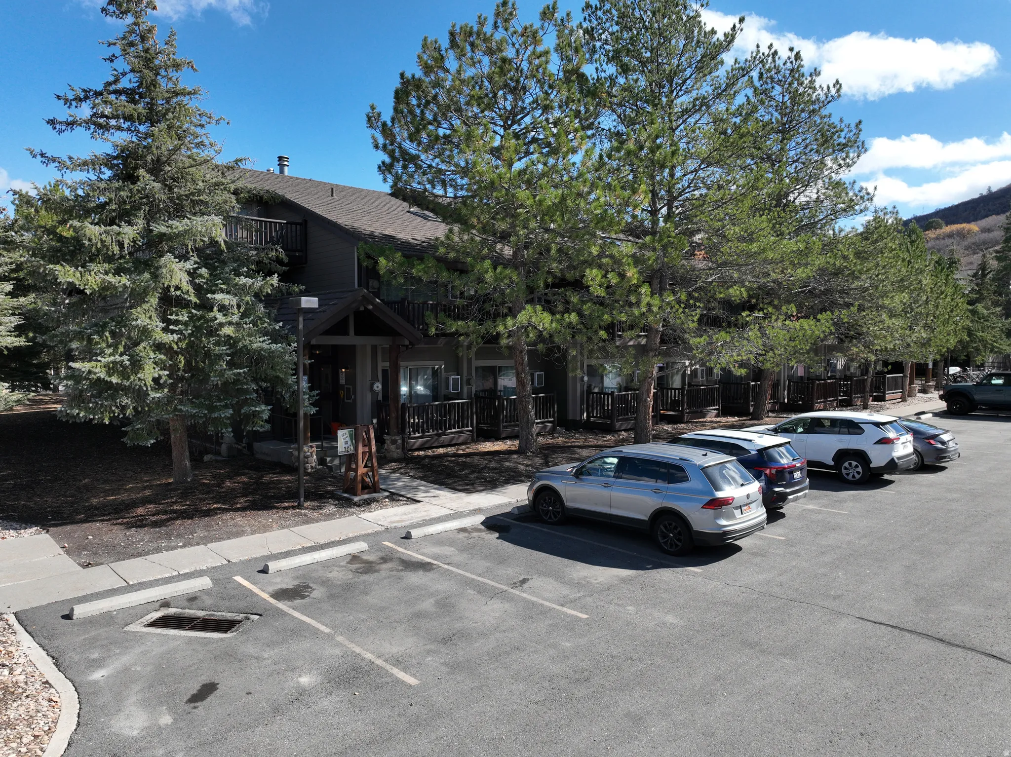 Multi-story structure with a dark exterior, featuring multiple private balconies with dark wood railings and a front porch entry with a gabled roofline