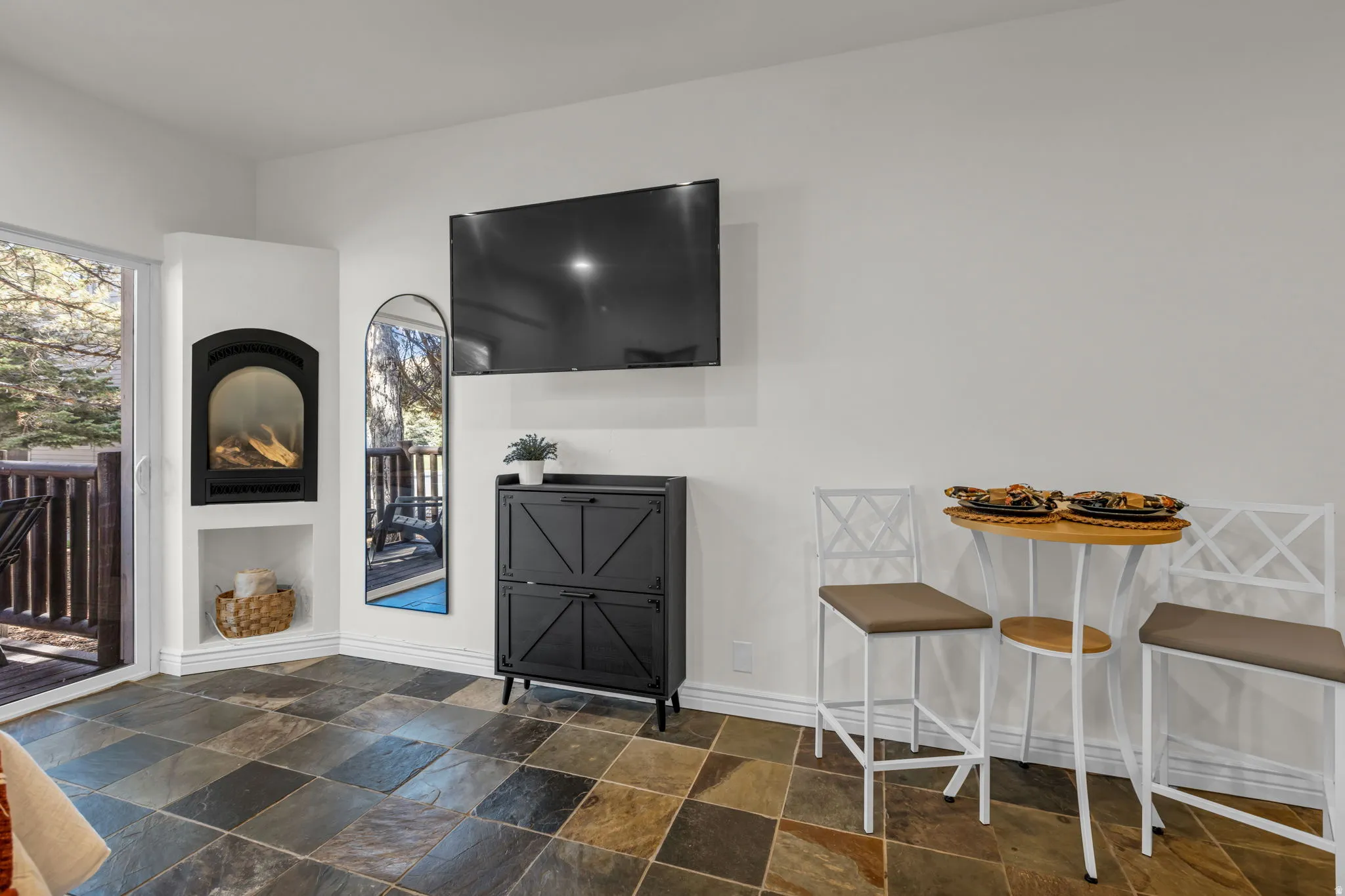 Living area featuring slate tile flooring, a built-in fireplace, and a sliding glass door opening to an outdoor balcony with wood railings