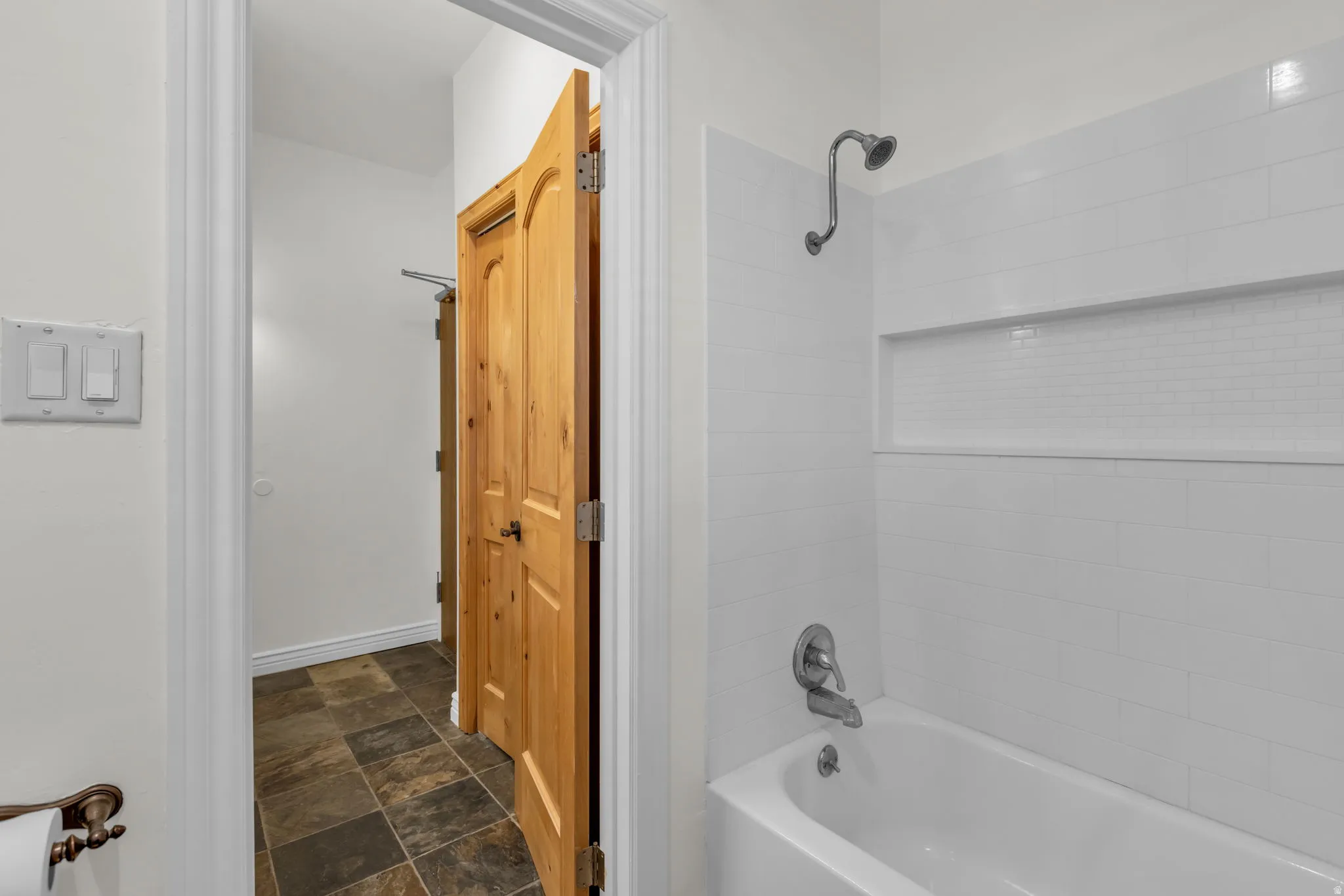 Bathtub with white subway tile surround, featuring a recessed niche with white mosaic tile