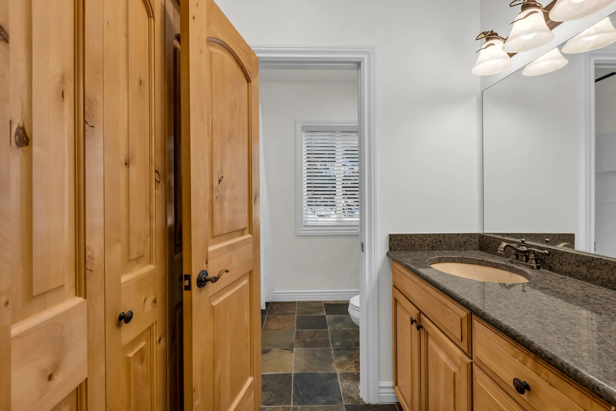 Bathroom vanity featuring a double sink with granite countertop and wood-finish cabinetry
