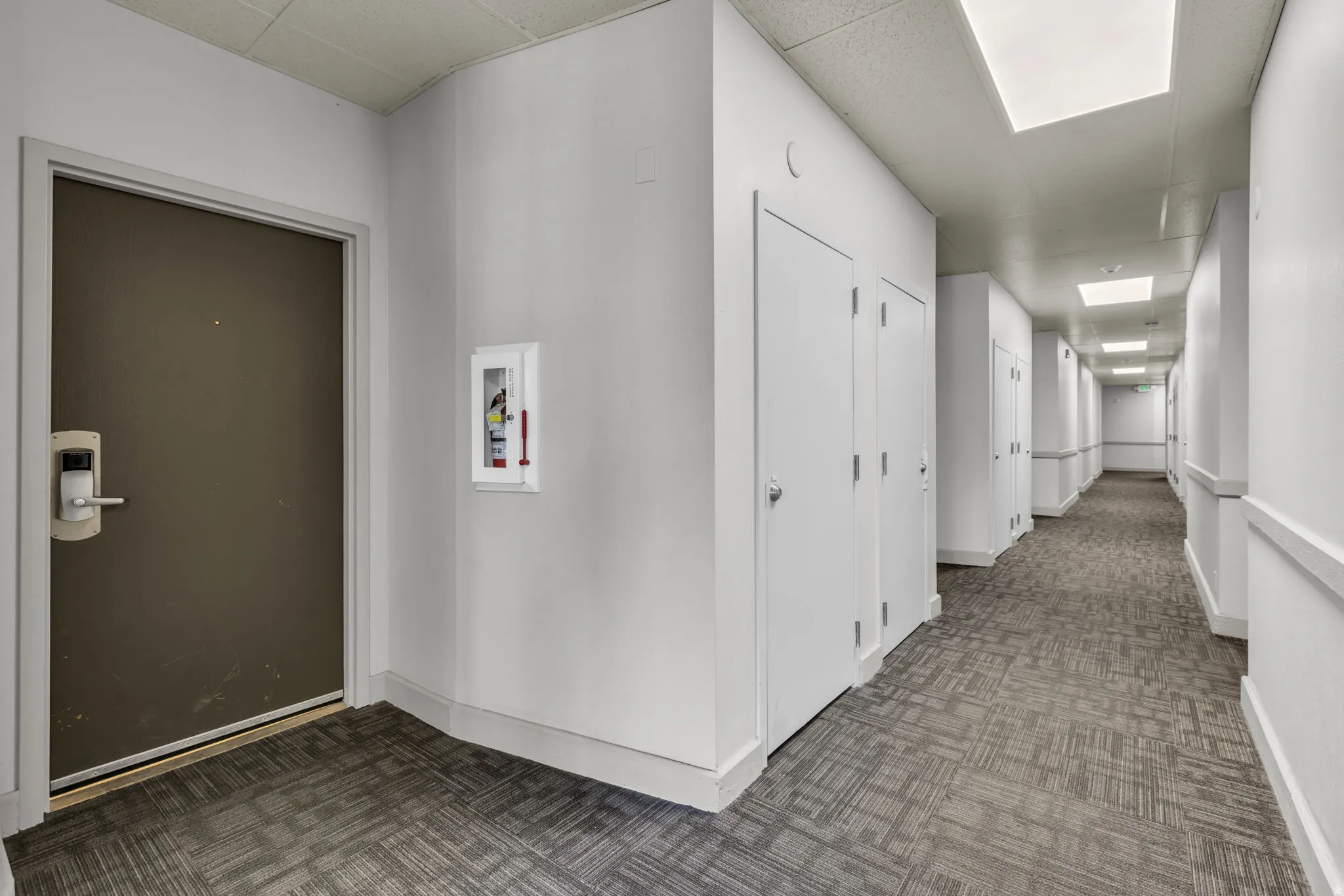 Hallway featuring recessed and flush mount lighting, patterned carpet flooring, and multiple white panel doors