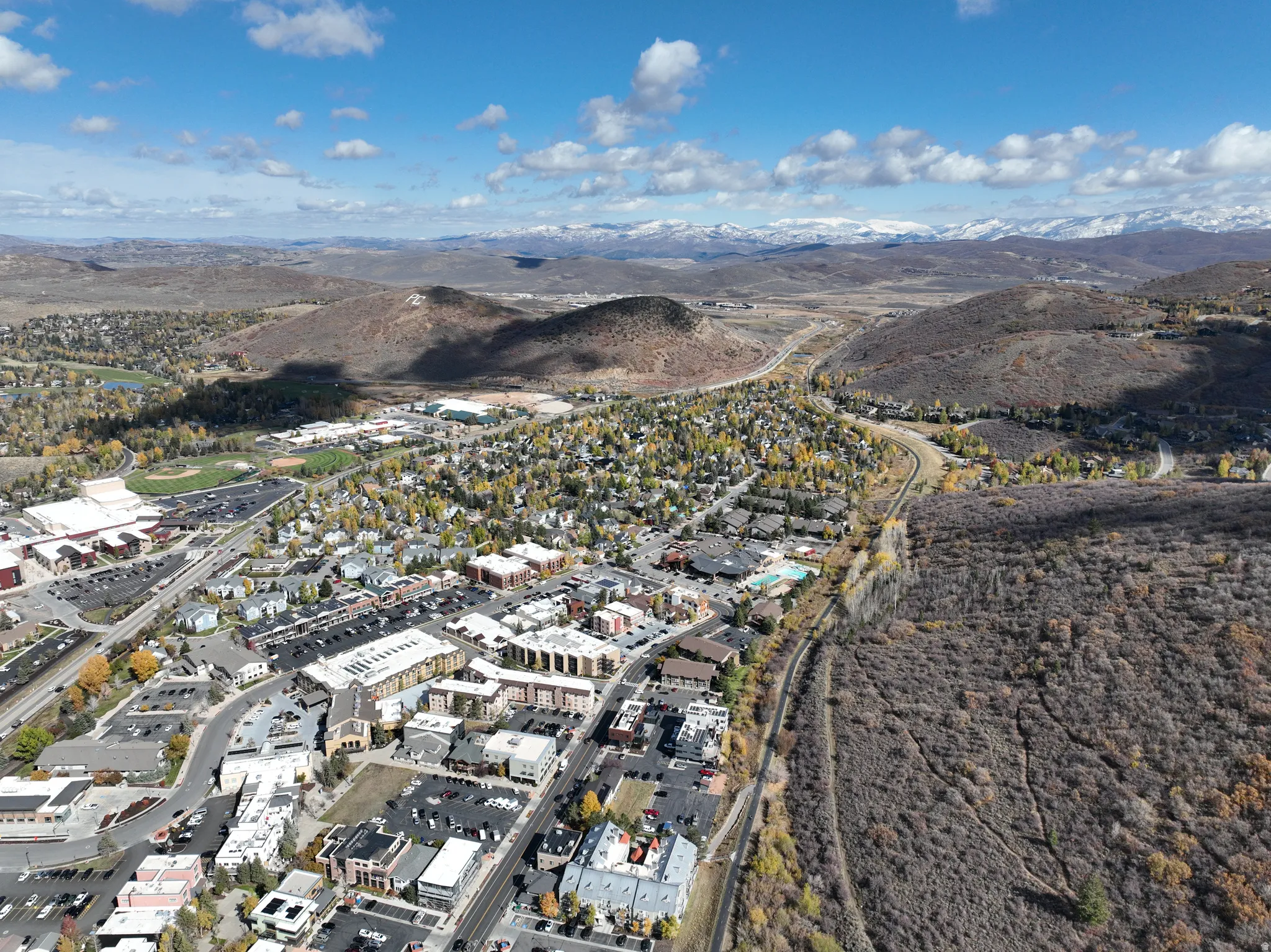 Aerial perspective showcasing a vibrant community with diverse architecture, surrounded by expansive natural landscapes