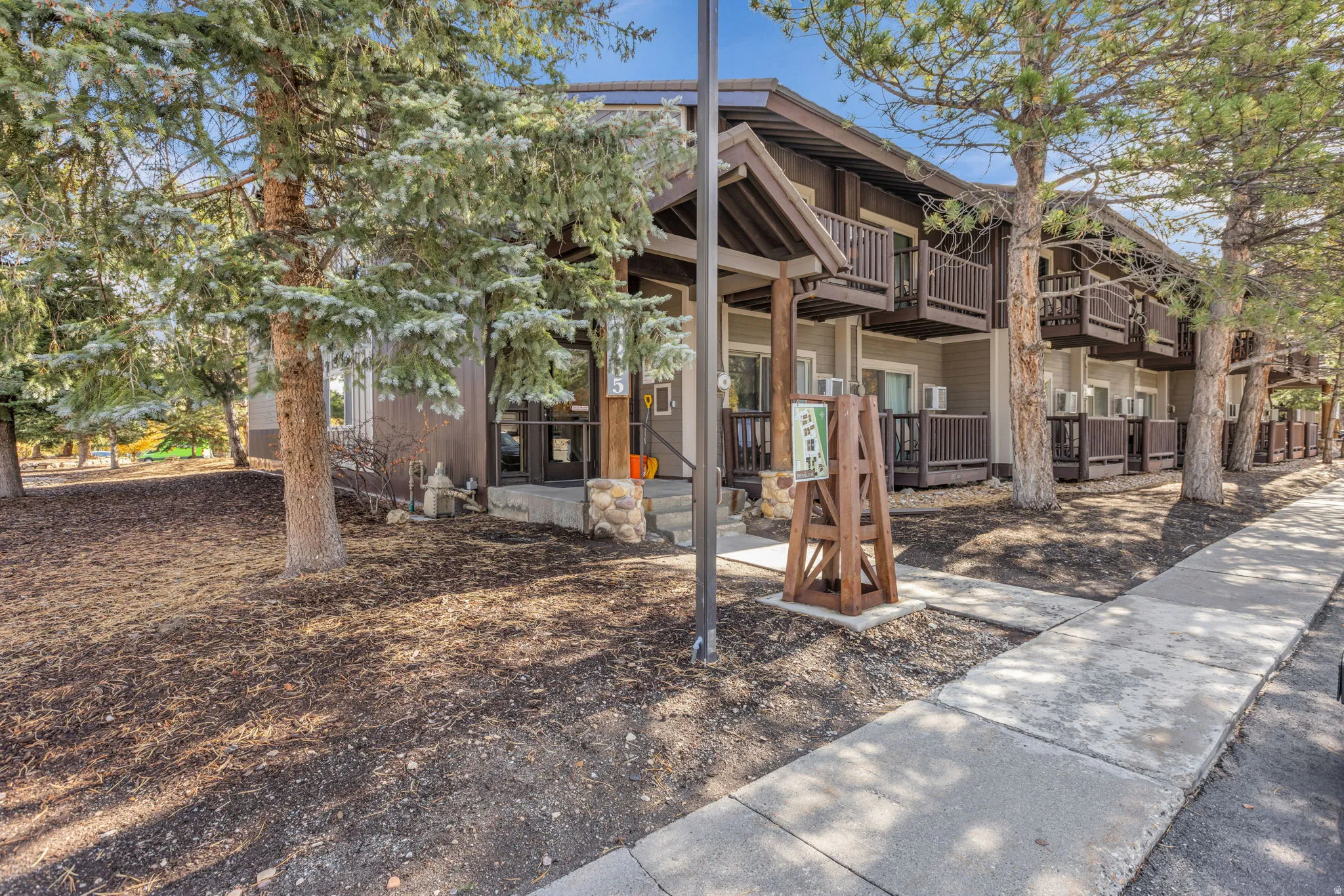 Multi-level building exterior featuring wood siding, dark wood trim, and multiple balconies with dark railings