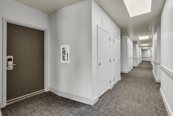 Hallway featuring recessed and flush mount lighting, patterned carpet flooring, and multiple white panel doors