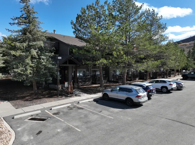 Multi-story structure with a dark exterior, featuring multiple private balconies with dark wood railings and a front porch entry with a gabled roofline