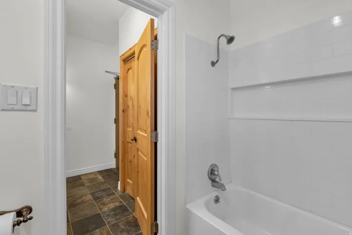 Bathtub with white subway tile surround, featuring a recessed niche with white mosaic tile