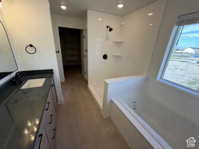 Recessed lighting, wood-finish flooring, and a vanity with an integrated sink and dark countertop