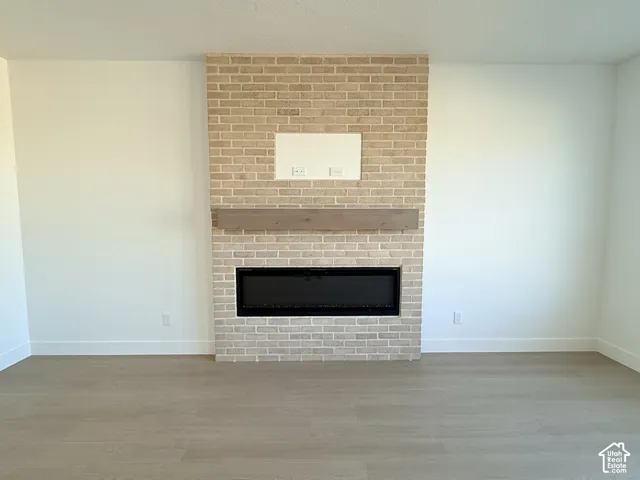 Brick fireplace with an integrated electric insert, a wood-finish mantel, and wood-finish flooring