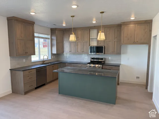 U-shaped kitchen with wood-finish cabinetry, dark countertops, and light tile backsplash